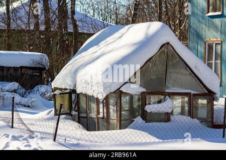 Greenhouse roof covered with snow after a long snowfall, a large layer of snow Stock Photo