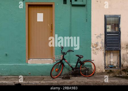 Kampong Glam, Singapore - December 19, 2022: A child bicycle against a green painted wall with no people Stock Photo