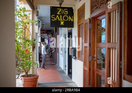 Kampong Glam, Singapore - December 19, 2022: A hair salon shop sign in the Muslim district of Kampong Glam with one barely recognizable man waiting ou Stock Photo