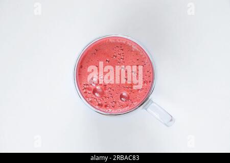 freshly squeezed red juice in a cup for breakfast with froth on top on an isolated background Stock Photo