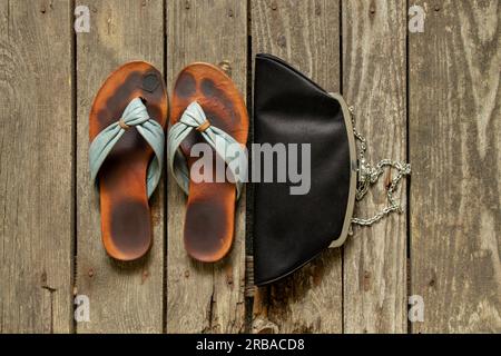 women's shoes through a finger and a small bag on a wooden background close up Stock Photo