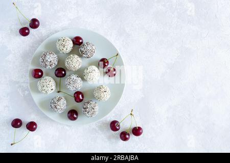 Homemade raw energy balls with cherry on the gray plate. Flat lay, close up, copy space on the gray background. Vegan sweets. Stock Photo