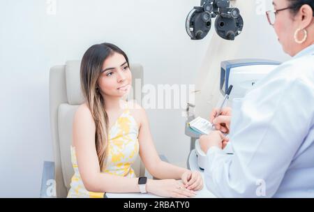 Female patient having consultation with optometrist in office. Optometrist with female patient taking notes in office Stock Photo