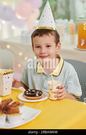 Portrait of smiling birthday boy having doughnut and sweet drink at party Stock Photo