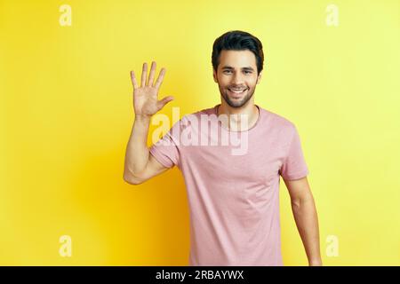 Portrait of smiling man with hand raised in greeting. High five, hello concept Stock Photo