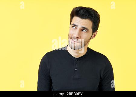Confused thoughtful man have a doubt over yellow background. Uncertain, thinking, pensive concept Stock Photo