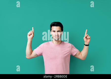 Handsome happy man pointing his finger showing empty copy space isolated on blue background. Presenting product and advertising concept Stock Photo