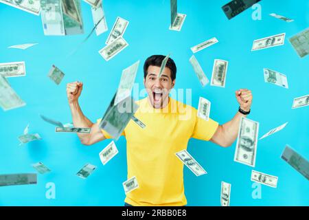 Happy excited man standing under money rain banknotes falling down. Success, business, and fortune concept Stock Photo