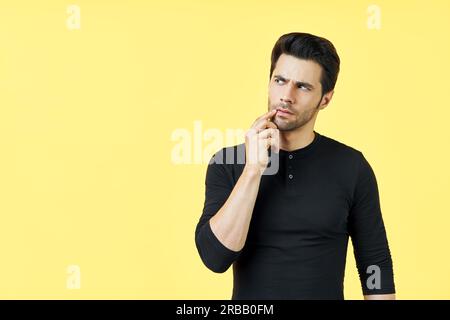 Confused thoughtful man have a doubt with copy space over yellow background. Uncertain, thinking, pensive concept Stock Photo