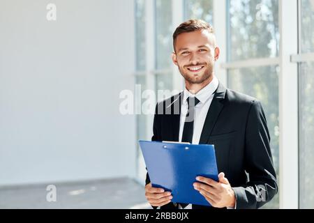 Handsome smiling businessman with clipboard in a bright modern office with copy space. business concept Stock Photo