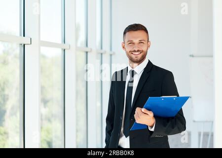 Handsome smiling businessman with clipboard in a bright modern office with copy space. business concept Stock Photo