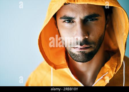Close up portrait of young handsome man in bright orange raincoat. Brutal male, lumberjack, fisherman concept Stock Photo