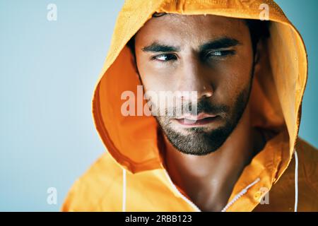 Close up portrait of young handsome man in bright orange raincoat. Brutal male, lumberjack, fisherman concept Stock Photo