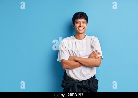 Happy Mixed-race man with crossed arms posing on blue background looking to camera with copy space. man beauty concept Stock Photo