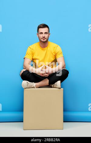 Handsome hipster man sitting on cube at studio. Mens beauty Stock Photo