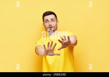 Young displeased man making stop gesture sign say no isolated on yellow background. Negative emotion, facial expression Stock Photo