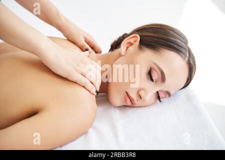 Close up portrait of young woman enjoying relaxing back massage at spa salon. Body care, rest concept Stock Photo