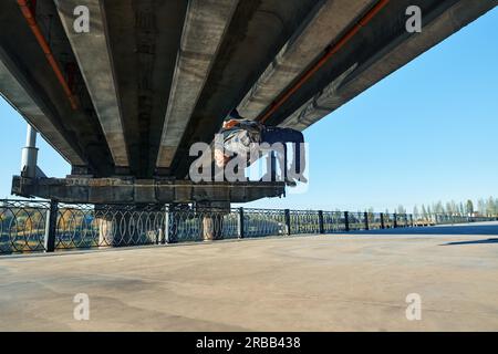 Young man break dancer doing somersault acrobatic stunts dancing on urban background. Street artist breakdancing outdoors Stock Photo