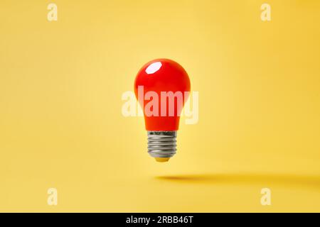 Red lightbulb levitate on yellow background. Idea, inspiration, motivation concept Stock Photo