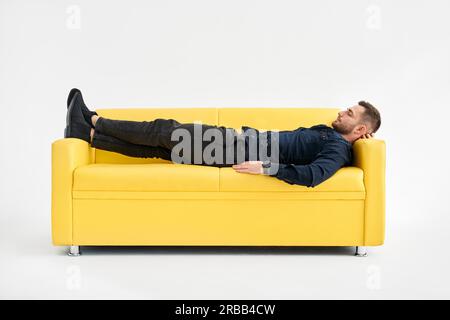 Young man relaxing alone on yellow sofa at home. Rest concept Stock Photo