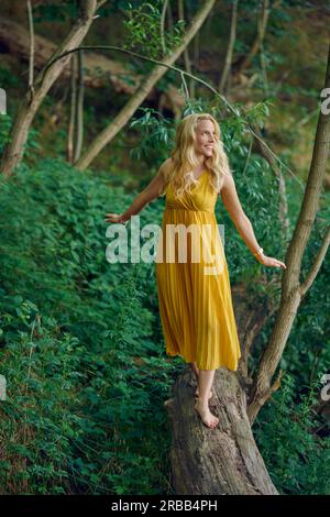Attractive smiling young woman wearing fancy universe print leggings  sitting on a tree log Stock Photo - Alamy