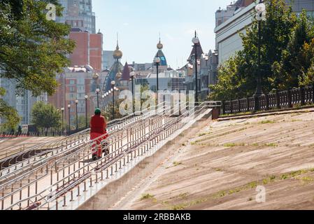 Ukraine, September 10, 2020, A woman climbs a long metal ramp for handicapped people, bicycles and people with strollers, near Natalka Park in the Stock Photo