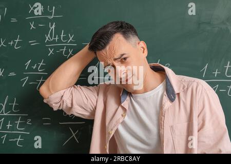 Tired Math teacher near chalkboard in classroom Stock Photo