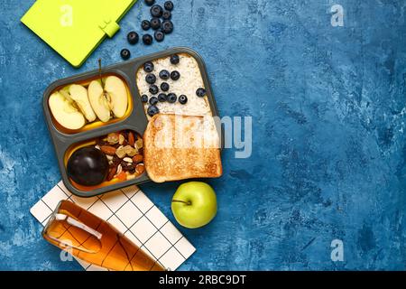 https://l450v.alamy.com/450v/2rbc9dt/bottle-of-lemonade-notebooks-and-lunchbox-with-tasty-food-on-grunge-dark-blue-background-2rbc9dt.jpg