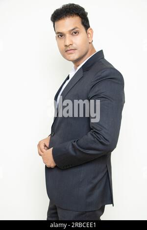 Handsome young indian businessman wearing suit standing posing isolated over white background. Corporate Concept. Stock Photo