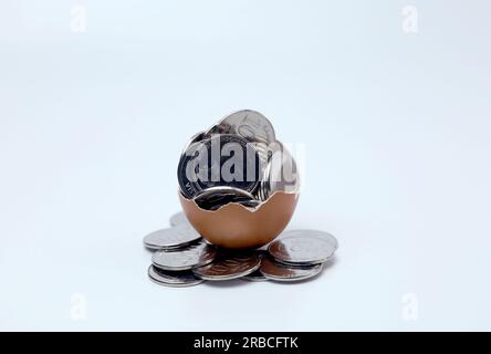 Coins inside cracked eggshell . Business concept for saving,investment, banking, finance. Indonesian coins currency. Stock Photo