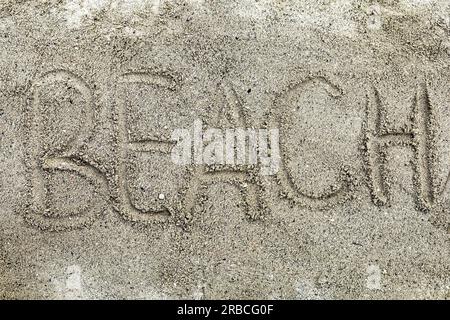 Handwritten word of beach on sand at the beach Stock Photo