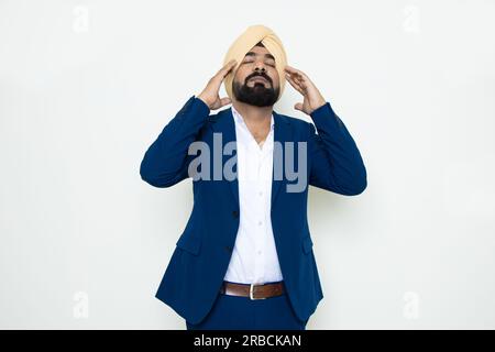 stressed indian sikh businessman wearing suit standing isolated over white background. Workload and depression. Stock Photo