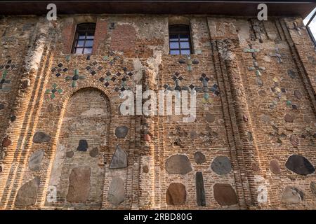 wall of an ancient orthodox church, monument of old brick russian architecture with texture of clay brick, decorated with inserts of colored stones in Stock Photo