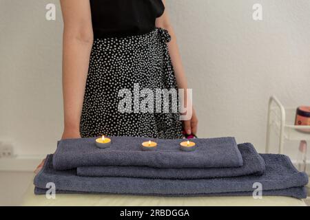 Burning candles and towels on table in spa salon, space for text Stock Photo