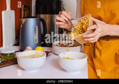 Closeup view of female hands putting steamed chickpeas into a bowl Stock Photo