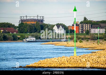 Cargo ship at low water on the Rhine near Duisburg-Homberg, view of Duisburg-Laar, houses on Deichstraße, gasometer of ArcelorMittal Hochfeld GmbH Sta Stock Photo