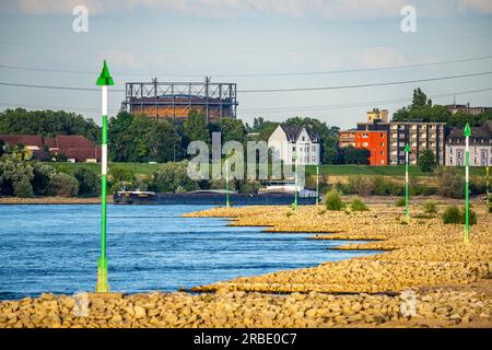 Cargo ship at low water on the Rhine near Duisburg-Homberg, view of Duisburg-Laar, houses on Deichstraße, gasometer of ArcelorMittal Hochfeld GmbH Sta Stock Photo