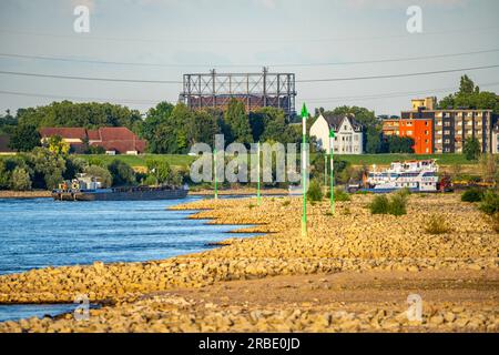 Cargo ship at low water on the Rhine near Duisburg-Homberg, view of Duisburg-Laar, houses on Deichstraße, gasometer of ArcelorMittal Hochfeld GmbH Sta Stock Photo