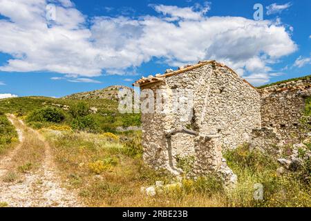 Ruins of a rural house in the La gallinera valley and the La Forada arch rock at the background. Costa blanca, Alicante, Spain. Stock Photo