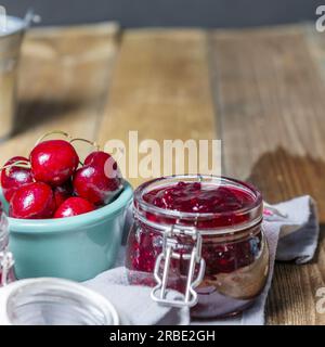 Red fruit jam in a glass jar on kitchen towels Stock Photo