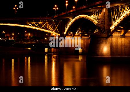 the Margaret bridge in Budapest at dusk. perspective side view. brightly illuminated steel arches. reflection on the water. tourism and travel concept Stock Photo