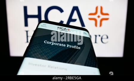 Mobile phone with website of US company HCA Healthcare Inc. on screen in front of business logo. Focus on top-left of phone display. Stock Photo