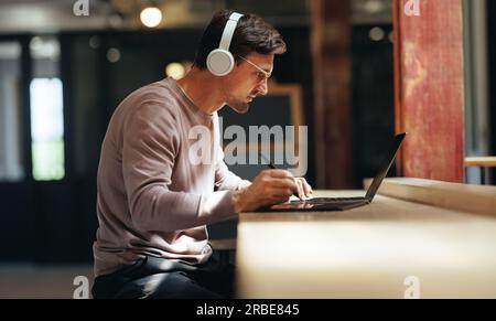 Freelance graphic designer working on a project in a coworking space. Creative business man using a laptop and a graphics tablet. Male design professi Stock Photo
