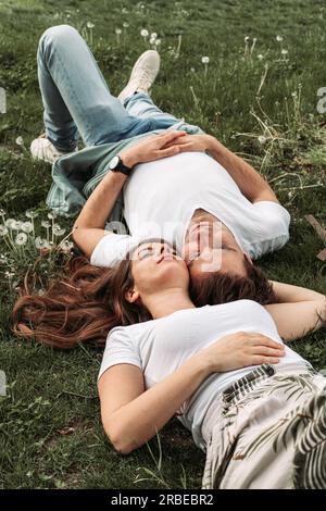 Young romantic couple lying in the grass, enjoying, relaxing Stock Photo