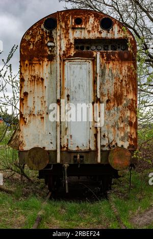 Old rusty freight carriage wagon abandoned on railway siding with green grass Stock Photo