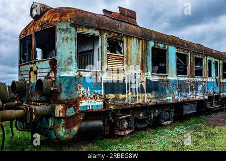 Old rusty passenger electric multiple unit train decommissioned and abandoned on railway siding on green grassy field Stock Photo