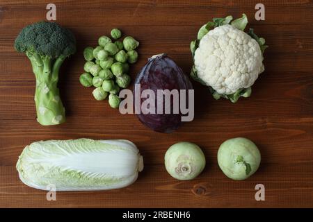 Different types of cabbage on a brown wooden table. View from above. Closeup. Broccoli, Brussels sprouts, kohlrabi, cauliflower, red cabbage, Chinese Stock Photo