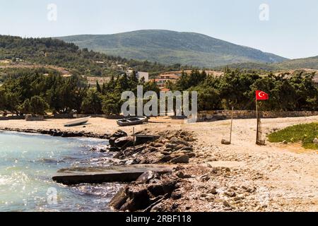 Quiet beach in Izmir, Turkey with juniper trees, Turkish Flag and wooden boats Stock Photo