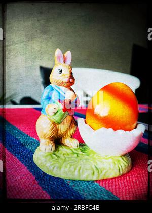 Easter bunny figurine with painted egg, nostalgic spring still life in warm sunlight, festive seasonal tradition Stock Photo