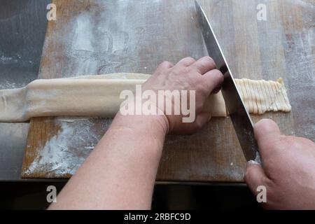 Hand-cutting fresh pasta by the male chef. Stock Photo